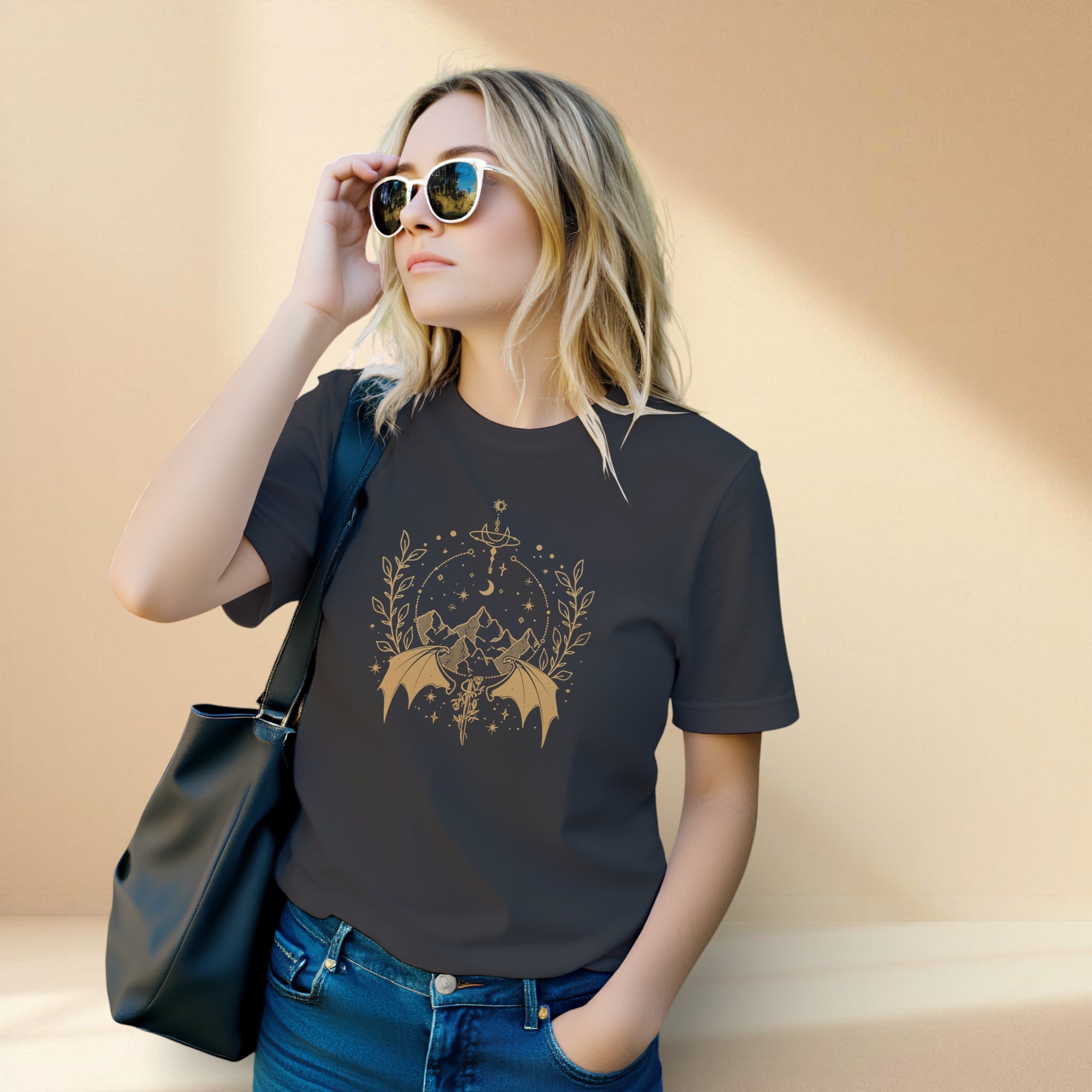 Woman wearing a black t-shirt with a graphic design, holding sunglasses and a black bag against a beige background