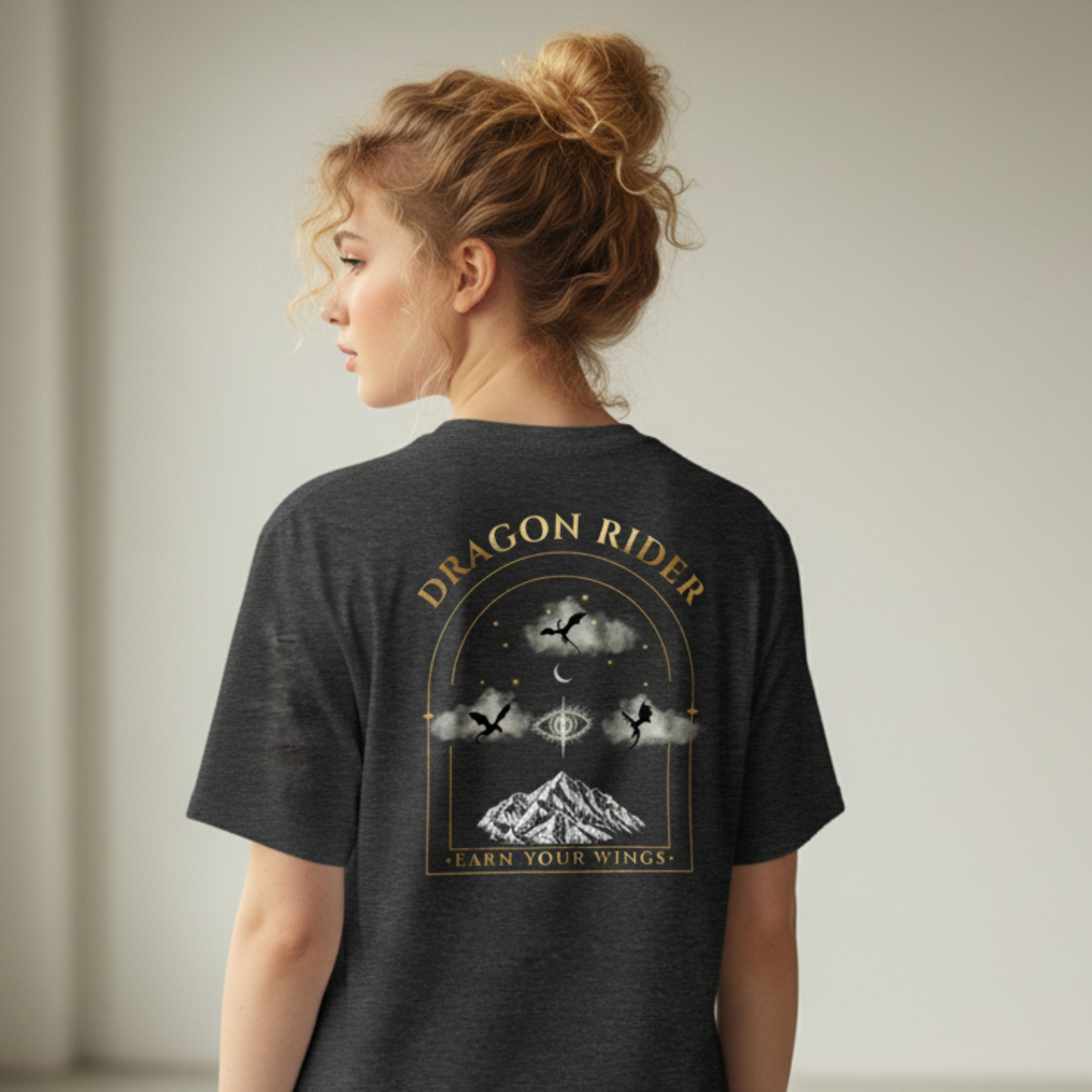 Woman wearing a black t-shirt with 'Dragon Rider' design in a minimalistic room.