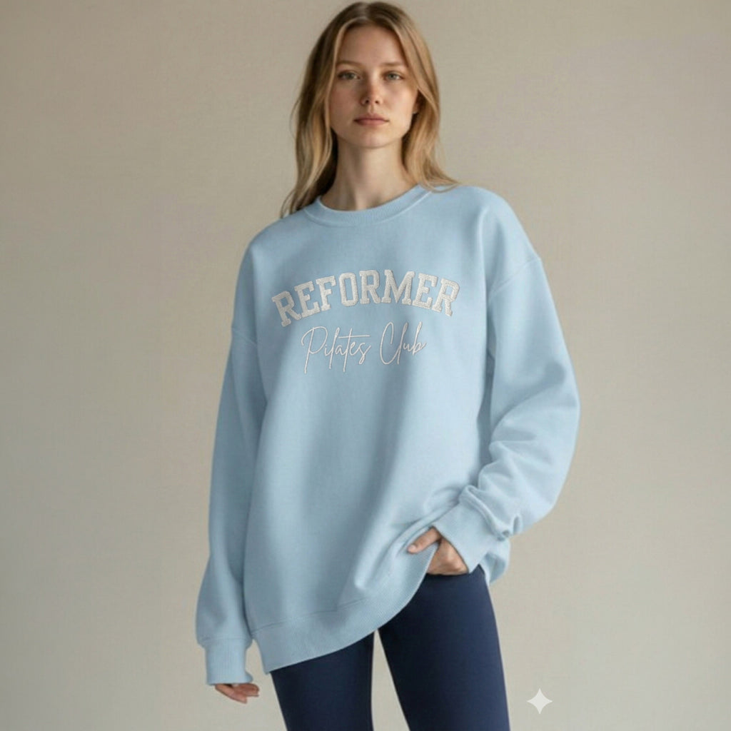 Reformer Pilates Club embroidered sweatshirt in light blue worn by model, oversized Pilates sweatshirt with white embroidery