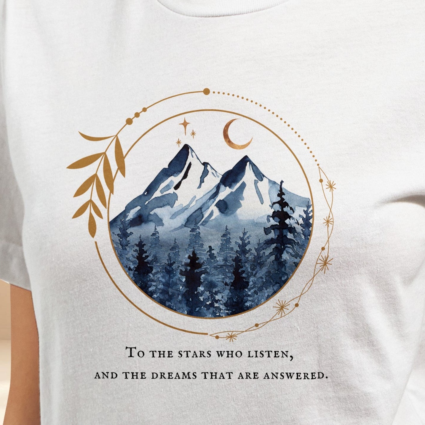 White t-shirt with mountain and moon design and text on a beige background