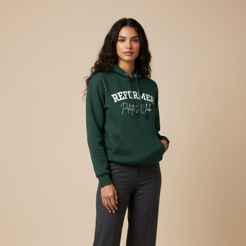 Woman wearing a green hoodie with text and gray pants on a beige background