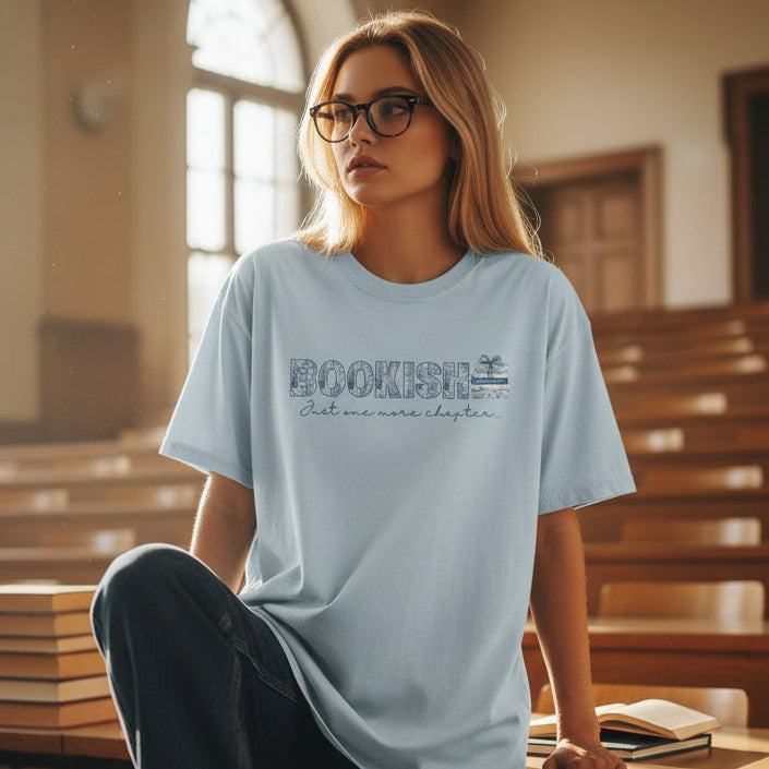 Person wearing a light blue t-shirt with text in an empty classroom